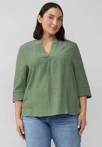 Lichtgroene, gestructureerde blouse met een V-hals en driekwartmouwen. Bevat subtiele verticale strepen en heeft een ontspannen silhouet.