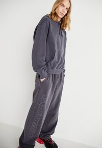 Koksgrå oversized hettegenser og matchende joggebukser med "STAR WARS" bokstaver. Stoffet ser mykt ut med en plysjaktig tekstur og kengurulomme.