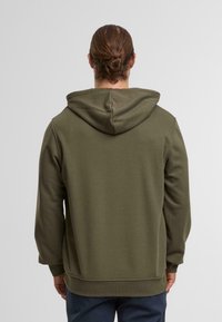 Hooded sweatshirt in olive green, made of soft fabric. Features a relaxed fit, ribbed cuffs, and hem, with a kangaroo pocket in front.