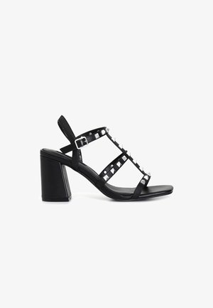 Black heeled sandal with an open toe, featuring multiple strap design, metallic pyramid studs, and a block heel for stability.