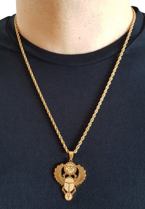 Collana in tono oro con catena a spirale e un pendente ornato con simbolo dell'occhio, ali, scarabeo e dettaglio ankh.