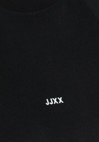 Black cotton t-shirt with a crew neck and white "JJXX" logo printed on the front. Features smooth texture and minimalistic design.