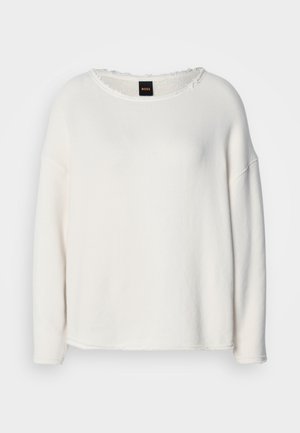 Biała bluza wykonana z miękkiego materiału, z okrągłym dekoltem, opuszczonymi ramionami oraz surowymi wykończeniami na krawędziach przy dole i dekolcie.