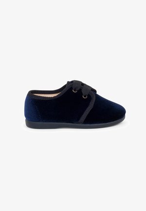 Scarpa in velluto blu navy con punta arrotondata, soletta imbottita e dettagli neri. Presenta un design con lacci e due passanti. Suola in gomma piatta.