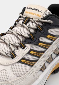 Boty Merrell Speed Strike 2 Trek s vrchním dílem z lehké béžové síťoviny, šedými akcenty, žlutými detaily a černými tkaničkami. Texturovaná podešev pro lepší úchop.