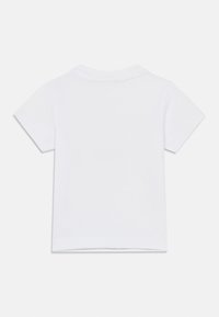 Απλό λευκό βαμβακερό T-shirt με κοντά μανίκια, απλωμένο επίπεδα και εμφανές το πίσω μέρος, με στρογγυλή λαιμόκοψη και απλή ραφή στο τελείωμα.