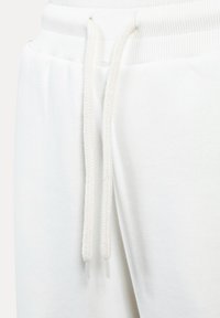 Weiße Sweatpants haben einen gerippten Bund mit verstellbaren, strukturierten Kordeln und einer weichen, glatten Stofftextur.
