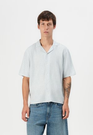 Chemise à manches courtes rayée bleu clair avec une coupe décontractée et un col en V, fabriquée dans un tissu léger. Fermeture à boutons décontractée à l'avant.