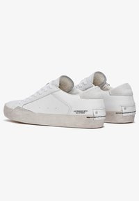 Witte leren sneakers met ronde neus, platte veters en grijze suede accenten. Kenmerkt zich door een verouderde afwerking en bedrukte tekst aan de zijkant.