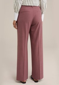 Rosa skräddarsydda byxor med breda ben, strukturerat tyg, bakfickor och midjehöjd. Stylar en randig skjorta.