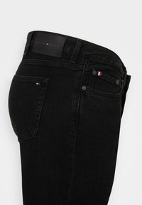 Czarne dżinsy o slim fit, z skórzaną naszywką w pasie z wytłoczonym logo marki oraz małym trójkolorowym logiem na tylnej kieszeni.