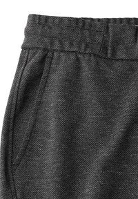 Pantalons noirs à taille élastique avec une texture tissée et des poches latérales, présentant un motif subtilement moucheté pour un détail supplémentaire.
