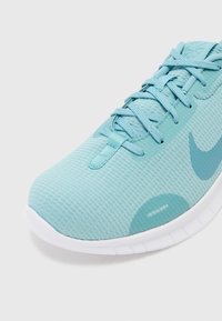 Baskets de course bleu clair en matériau mesh, affichant un design texturé, des lacets plats et une semelle blanche avec des motifs distinctifs.