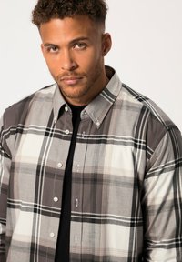 Camicia a maniche lunghe a quadri in tonalità di grigio, bianco e nero; presenta un colletto a punta, bottoni frontali e tessuto testurizzato.