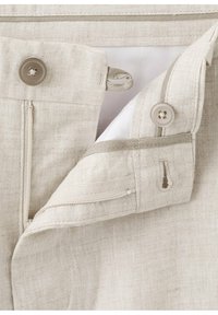 Ceinture de pantalon en lin beige avec deux boutons, des boutonnières et une fermeture éclair partiellement ouverte montrant la doublure intérieure blanche.