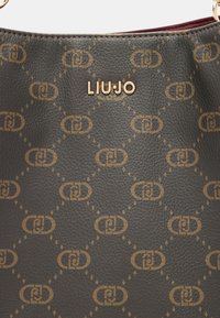 Borsa a mano in pelle verde con un motivo geometrico ripetuto in tonalità oro, con il logo dorato "LIU-JO" nella parte superiore. Texture liscia, cuciture accurate.