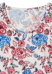 Tissu blanc avec un motif floral rouge et bleu, montrant un col rond et une étiquette de vêtement indiquant "CECIL."