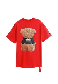 Camiseta roja de manga corta con un gráfico de oso de peluche texturizado en la parte posterior, con un detalle de cinturilla negra y una etiqueta en la manga.