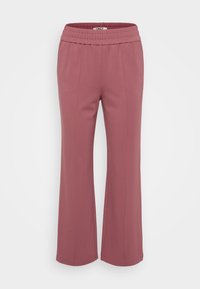 Světle růžové široké kalhoty vyrobené z měkké, pružné látky s texturovaným elastickým pasem a minimálními švy.