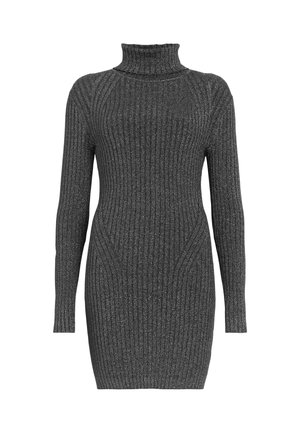 Mujer con un minivestido gris de punto acanalado con cuello alto, bolso negro de bandolera y botas negras de combate con cordones.