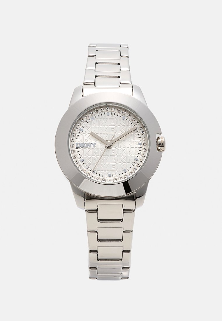 Reloj de acero inoxidable plateado con una caja redonda, esfera blanca texturizada y acentos de cristal alrededor del bisel, que presenta un logo de DKNY.