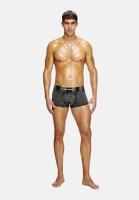 Boxer in denim grigio scuro con finitura texturizzata, dotati di patta con bottoni e dettagli a contrasto in vita. Modello in piedi a piedi nudi.