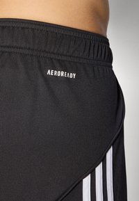 Juoda sportinė šortai su tekstūruotu audiniu. Pasižymi pločiu elastiniu juosmeniu ir trimis aiškiai matomomis baltomis juostelėmis šone. Rodyklė "AEROREADY".