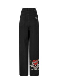 Jeans de pierna ancha negros con cintura alta, que cuentan con bolsillos traseros y un diseño bordado de calavera y corazón en la pierna izquierda. Textura de mezclilla suave.