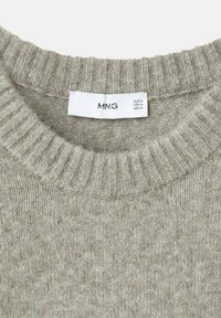 Primer plano del escote de un suéter de punto gris claro con una etiqueta blanca de la marca MNG que muestra la talla mediana.