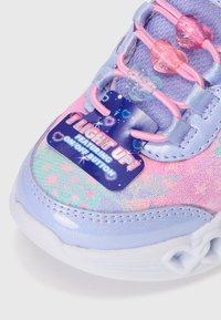 Sneaker luminoso con una toma alta in gradiente lilla e rosa, dettagli in plastica trasparente, charm a forma di cuore e un'etichetta prominente.