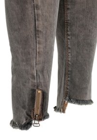 Grijze denim broek met een licht versleten afwerking. Voorzien van ritsen bij de enkels en een rafelige zoom. Contraststiksels langs de naden.