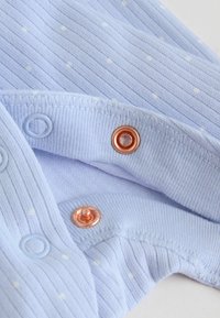 Tissu bleu clair avec de petits points blancs et des rayures verticales, doté d'une fermeture à bouton-pression en métal couleur cuivre partiellement enclenchée.