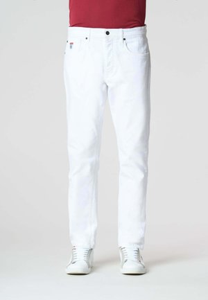 Pantaloni in denim bianco con vestibilità dritta, cinque tasche, chiusura con bottone nero e branding discreto. Indossati con sneakers bianche.
