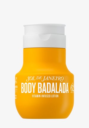 Jasnożółta butelka balsamu do ciała Sol de Janeiro Body Badalada z dodatkiem witamin, z białą zakrętką typu flip-top i wyraźnym białym napisem z przodu.