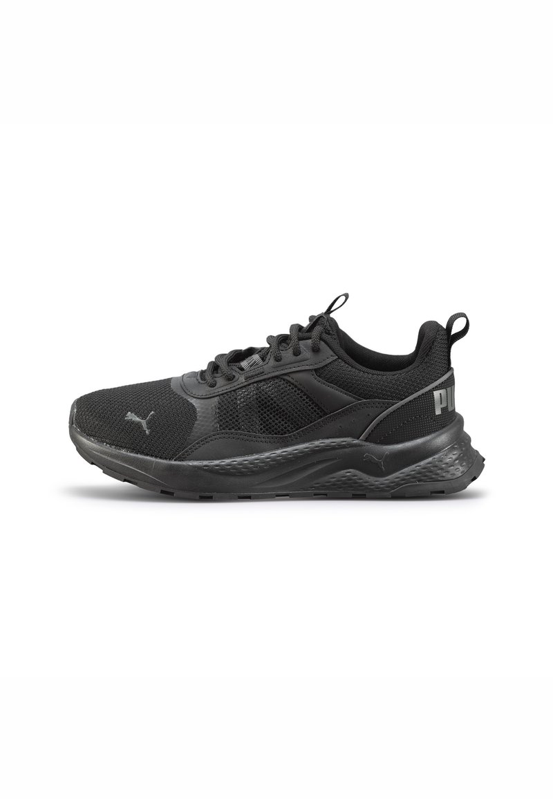 Zapatilla deportiva negra con materiales de malla y sintéticos, punta redondeada, acentos texturizados y detalle del logotipo en el lateral.