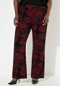 Zwarte broek met een rood bloemenpatroon, met een losse pasvorm en een gestructureerde stof. Gecombineerd met zwarte hoge hakken.
