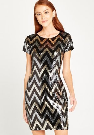 Kurzärmliges, figurbetontes Kleid, das mit schwarzen, silbernen und goldenen, in Chevron-Muster angeordneten Pailletten bedeckt ist. Es hat einen runden Halsauschnitt und eine Länge bis oberhalb des Knies.