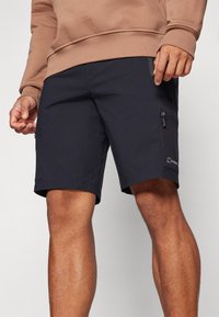 Pantaloni corti blu scuro con vestibilità regolare, realizzati in tessuto leggero. Presentano una tasca laterale con zip e un accento con il logo.