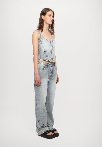 Light blue denim crop top with square neckline and exposed stitching, paired with loose-fitting light blue jeans featuring embroidered accents and frayed hem.