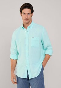  Lichtblauwe button-up shirt van gestructureerde stof, met een borstzak en opgerolde mouwen. De knopen zijn wit en glad.
