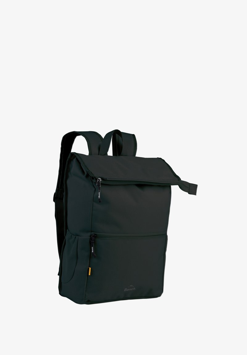 Sac à dos en tissu vert avec une fermeture à rabat, des poches zippées, des bretelles rembourrées et des détails en or. Texture lisse et forme rectangulaire.
