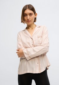 Cămașă roz deschis cu dungi, cu nasturi, buzunar pe piept, mâneci lungi și croială lejeră. Țesătură moale cu textură fină.