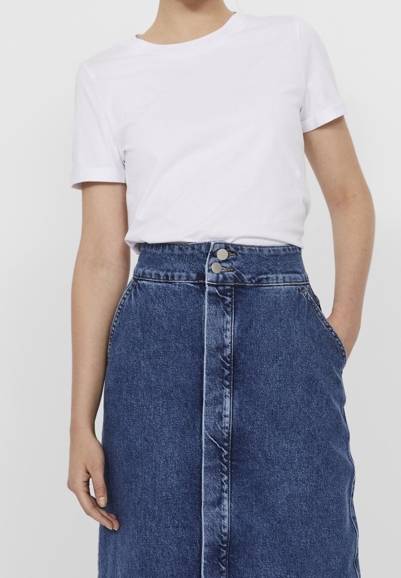 Vit kortärmad t-shirt i kombination med en högmidjad blå denimkjol med två framknappar och sidofickor.