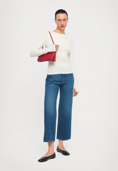 White long-sleeve top, blue wide-leg jeans, black flats, and a red leather handbag. Simple design and fitted silhouette with smooth texture.