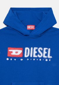 Felpa con cappuccio blu in cotone. Presenta un grande logo grafico bianco e rosso "DIESEL" sul davanti. Texture morbida con una tasca frontale.
