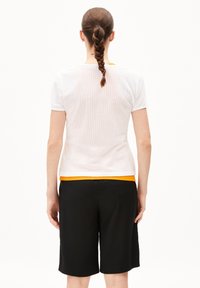 White mesh short-sleeve top layered over an orange shirt, paired with black knee-length shorts. Smooth texture, casual fit.
