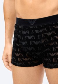 Zwarte boxershorts van doorschijnende stof met een all-over logo patroon. Elastische tailleband met een logo-accent. Slank aansluitend ontwerp.