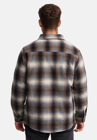 Rutet skjorte med knapper og ryggskjorte, i brune, blå og kremfargede toner. Laget av vevd stoff med en teksturert overflate.