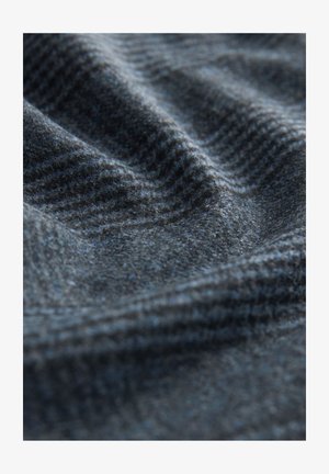 Wollen stof in donkerblauwe tinten, met een gestructureerd, golvend patroon. Het oppervlak lijkt zacht en geweven, met verschillende tinten blauw door elkaar gemengd.