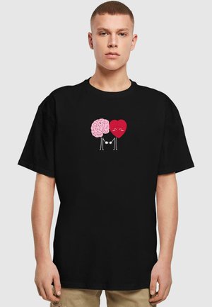 Sort bomulds T-shirt med et pink hjernevare og en rød hjertegrafik, der holder hænder, med enkle cartoon-lignende konturer og smilende ansigtstræk.